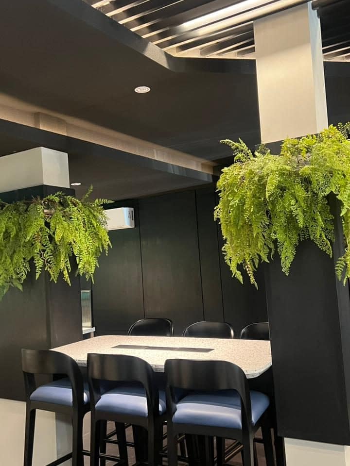 Meja bar dengan kursi tinggi berbantalan biru di area kantor EVOLUTION