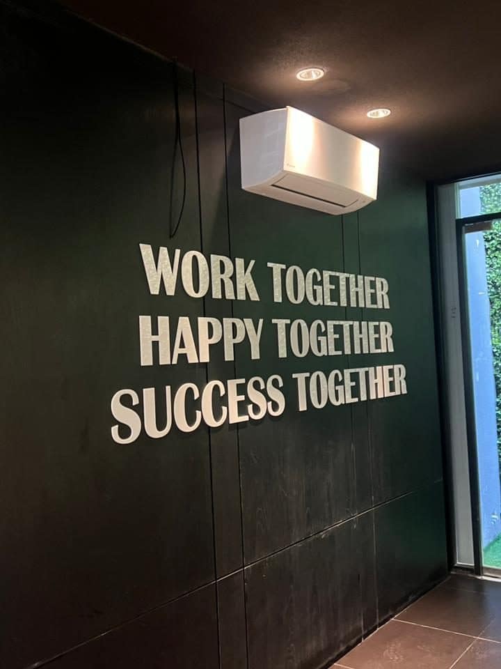 Tulisan Work Together, Happy Together, Success Together di dinding kantor EVOLUTION
