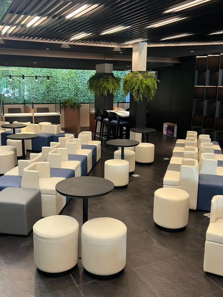 Area lounge kantor EVOLUTION dengan kursi putih dan tanaman gantung